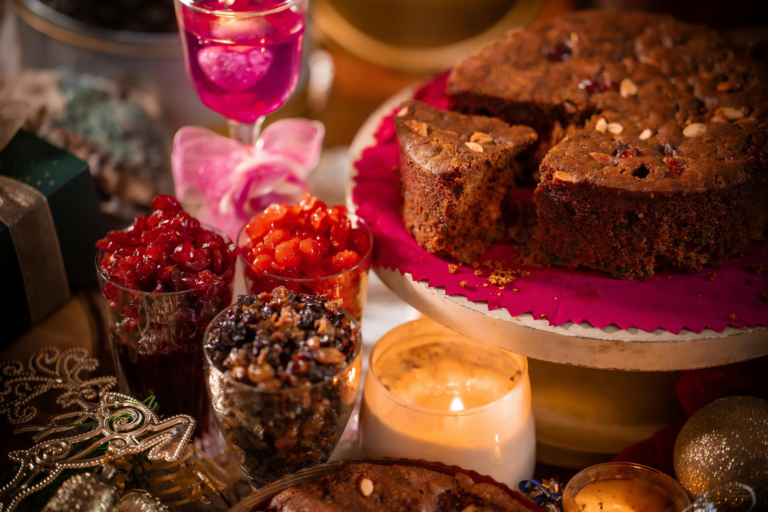 Delicious holiday fruitcake surrounded by candles and festive decorations, perfect for celebrations.