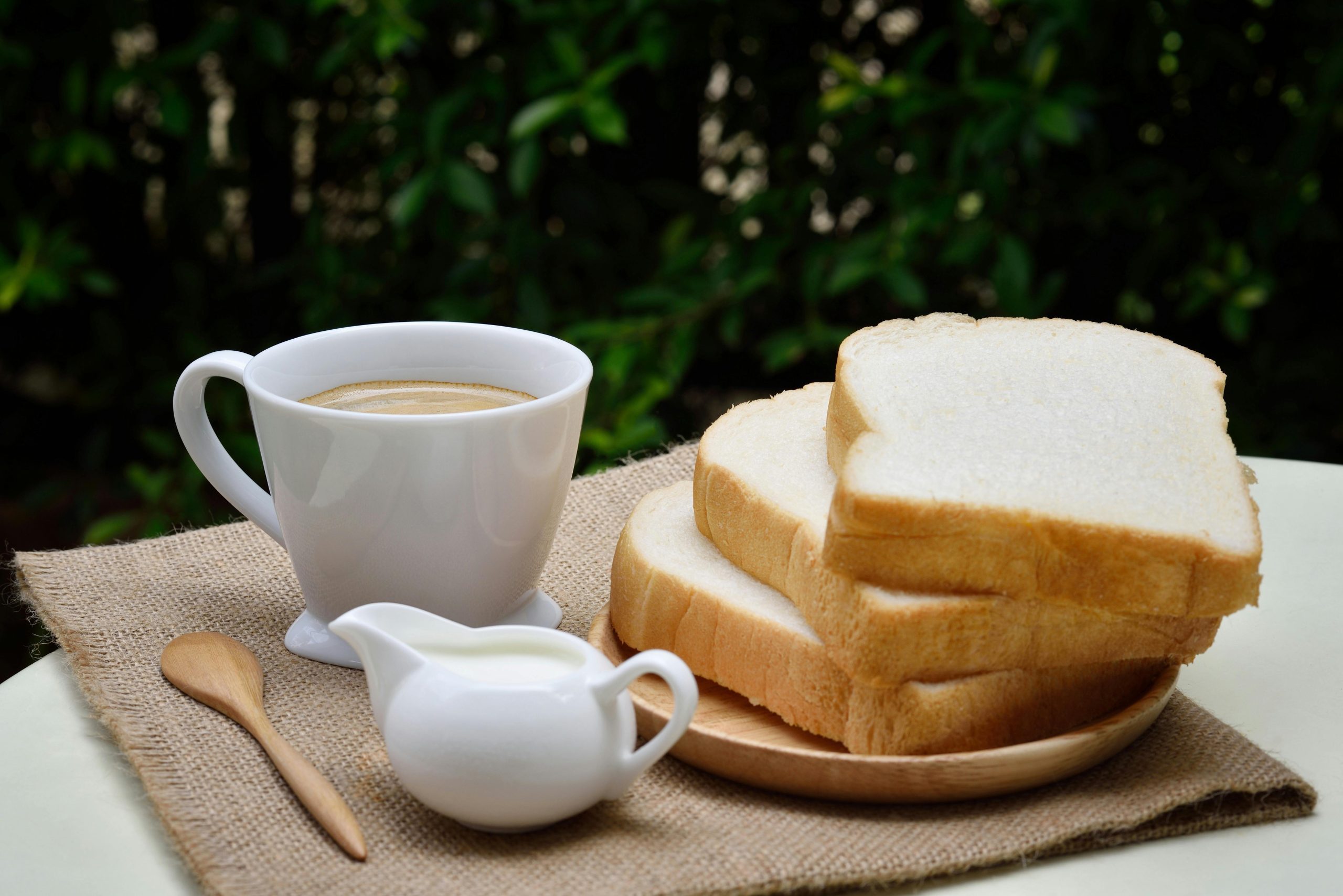 A cozy breakfast setup with fresh bread and a steaming cup of coffee outdoors.
