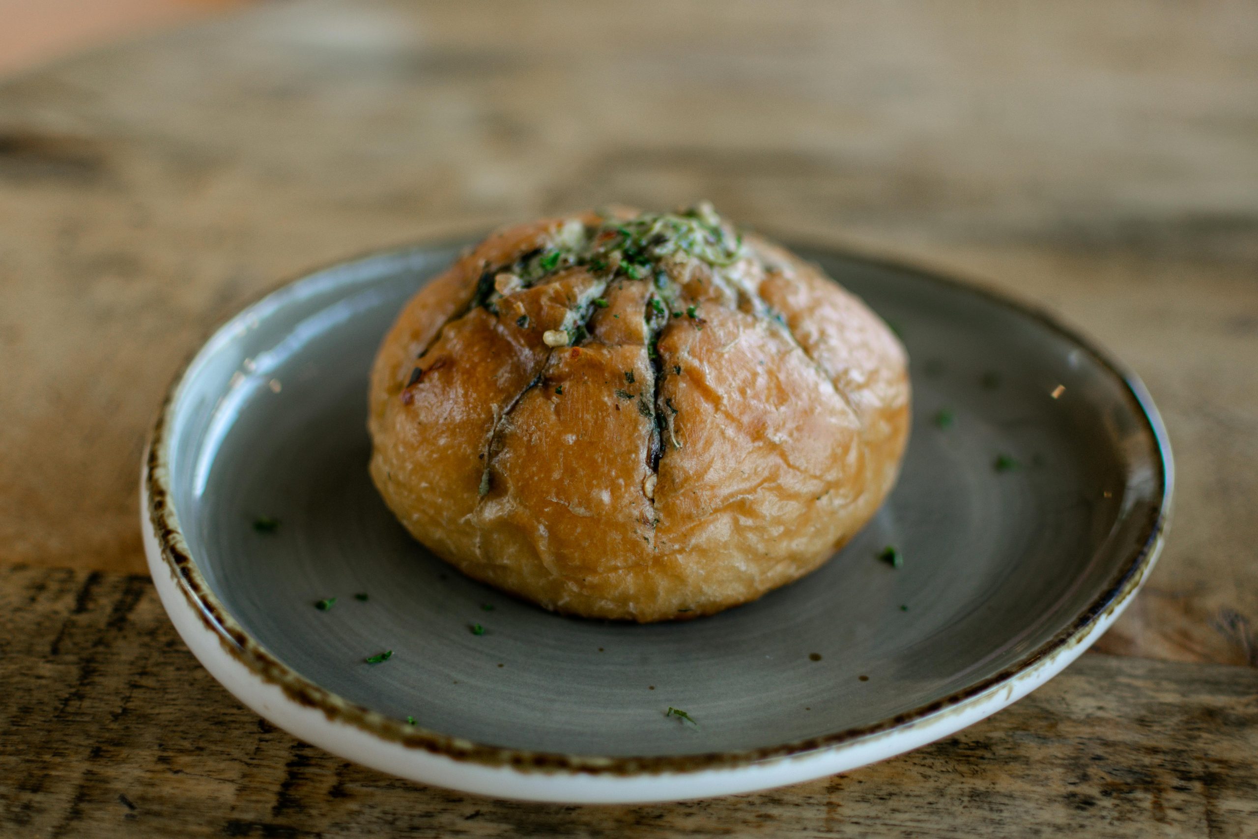 A tempting garlic bread bun served on a ceramic plate, highlighting its golden crust.
