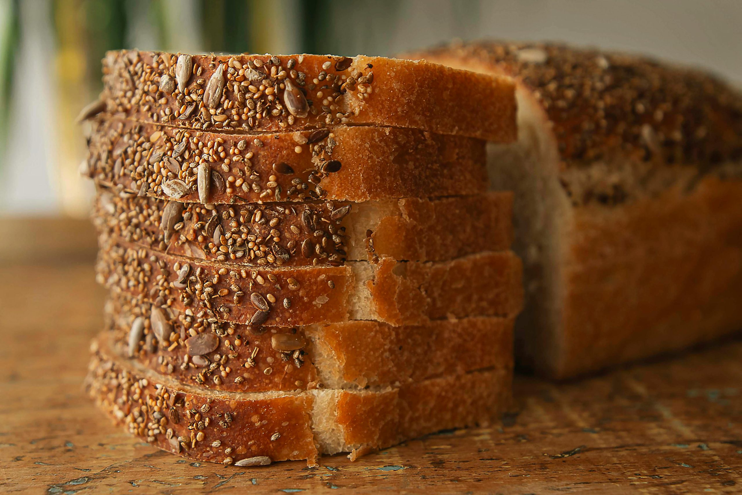 Close-up of nutritious sliced multigrain bread on a wooden table, showcasing seeds and texture.